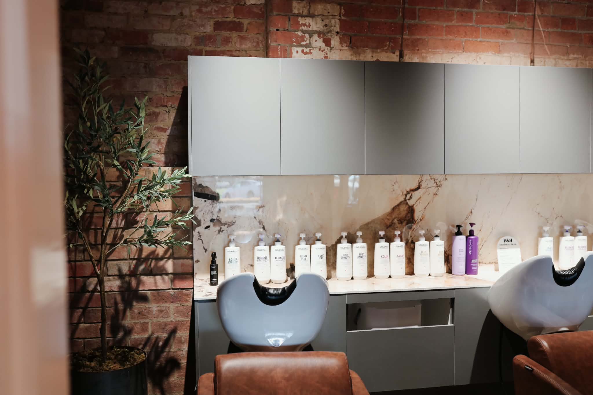 Reception desk with fluted timber detailing and exposed brick at Hair and Halo Studio